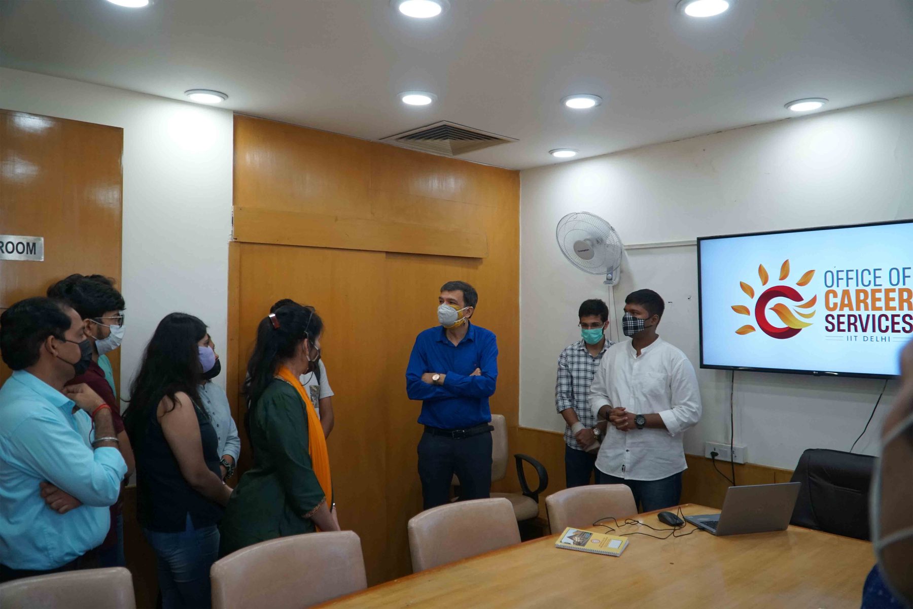The Director of IIT Delhi interacting with the OCS team, the new logo displayed on a screen behind them.